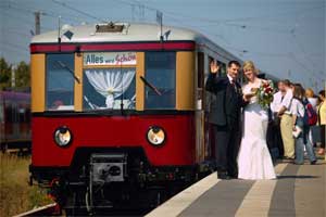 Zug am Bahnsteig mit dem Hochzeitspaar daneben